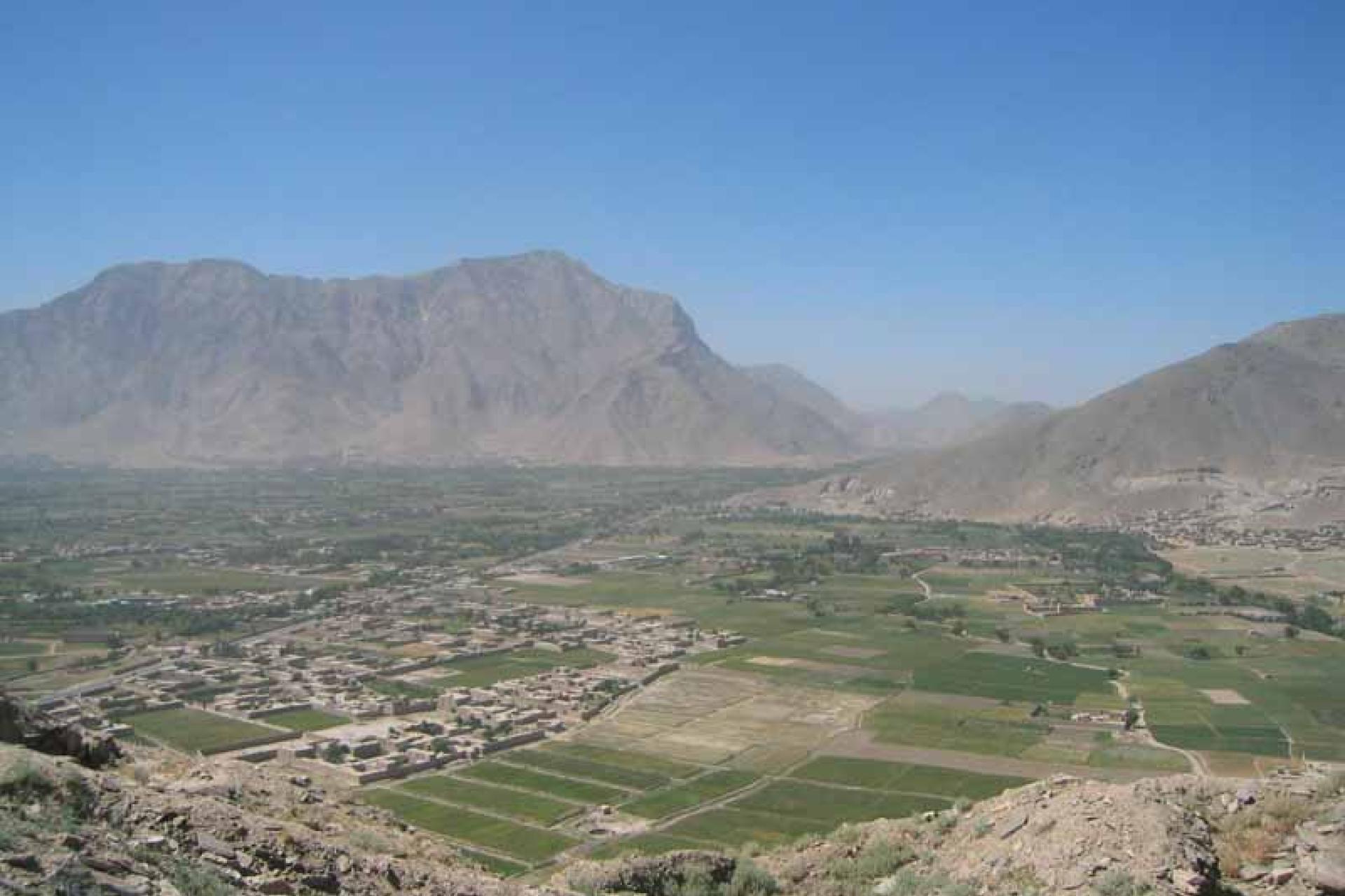 Foto van de Baluchi vallei in Afghanistan met daarop huizen, weilanden en op de achtergrond bergen