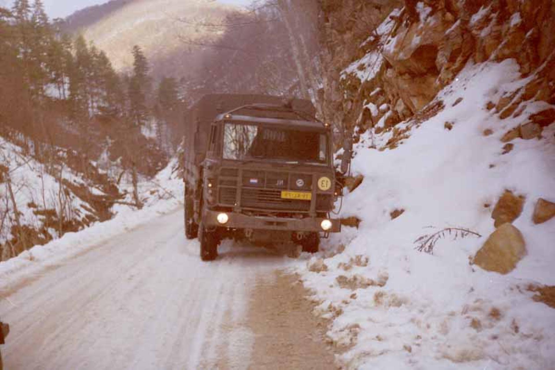 Militaire truck rijd door bergen op besneeuwde weg