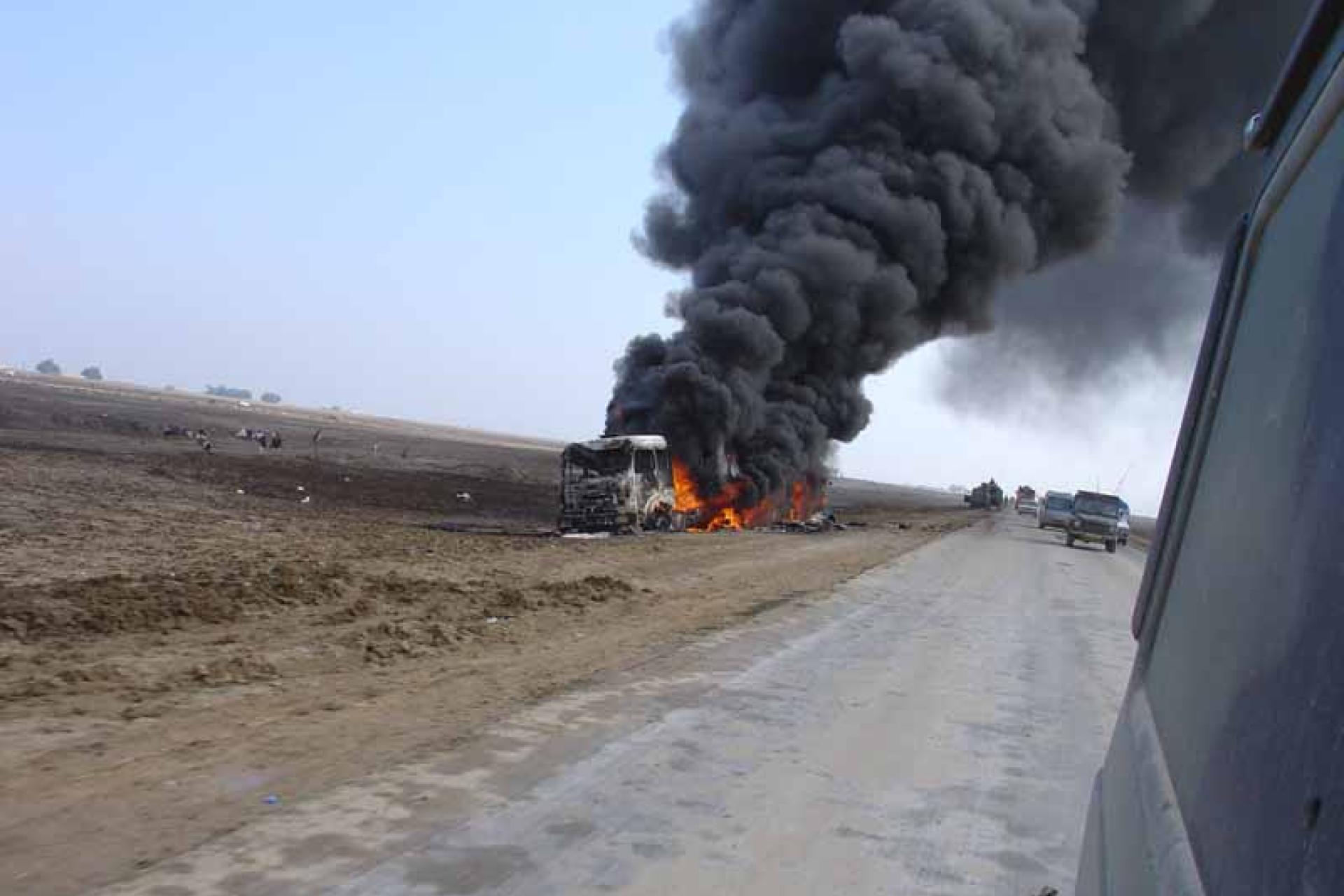 Militair voertuig staat in brand naast de weg in Irak
