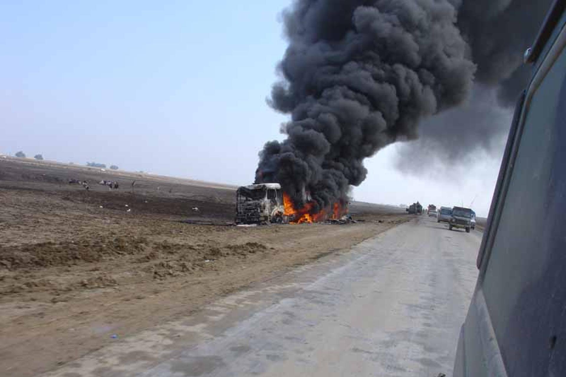 Vergroot afbeelding Militair voertuig staat in brand naast de weg in Irak