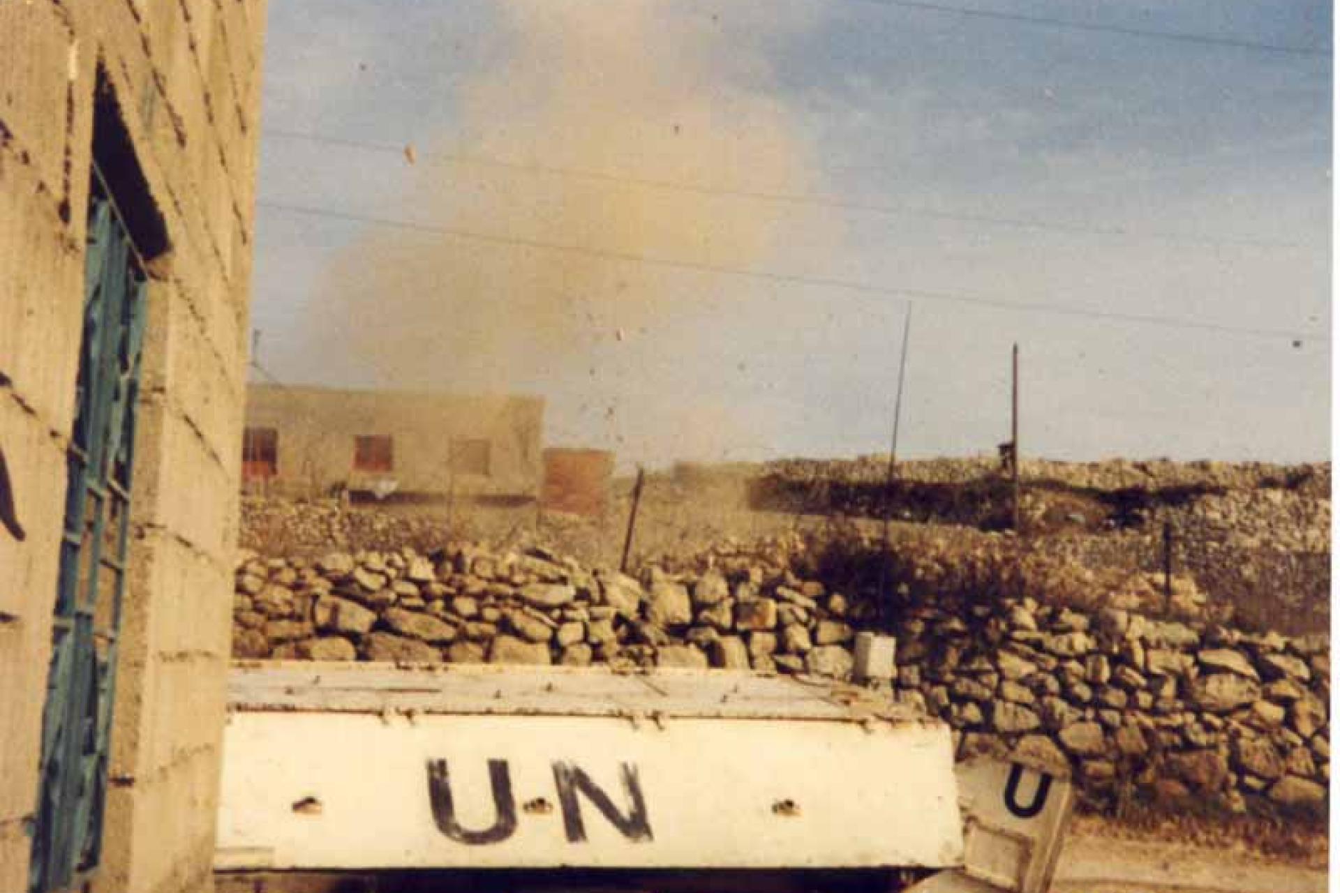 VN post met gebouw en muren met op de achtergrond een explosie